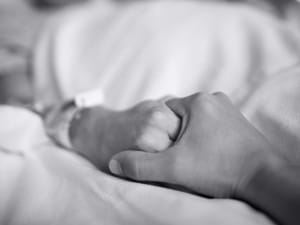Holding the hand of a loved one in a hospital bed