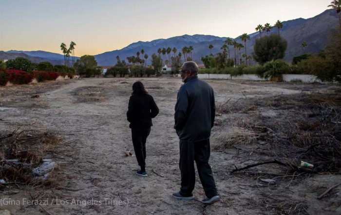 Joe Abner and his wife, Vera, walk through a vacant lot that was once part of the Section 14 community in Palm Springs. Abner was 13 when his family fled Section 14, which the city ultimately leveled to make way for luxury developments in the 1960s. Photo by Gina Ferazzi Los Angeles Times
